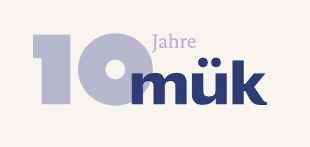 Das Bild zeigt den Text '10 Jahre mük' in einem stilisierten Design, wobei die Nummer '10' in Grau und 'Jahre mük' in Blau hervorgehoben ist.