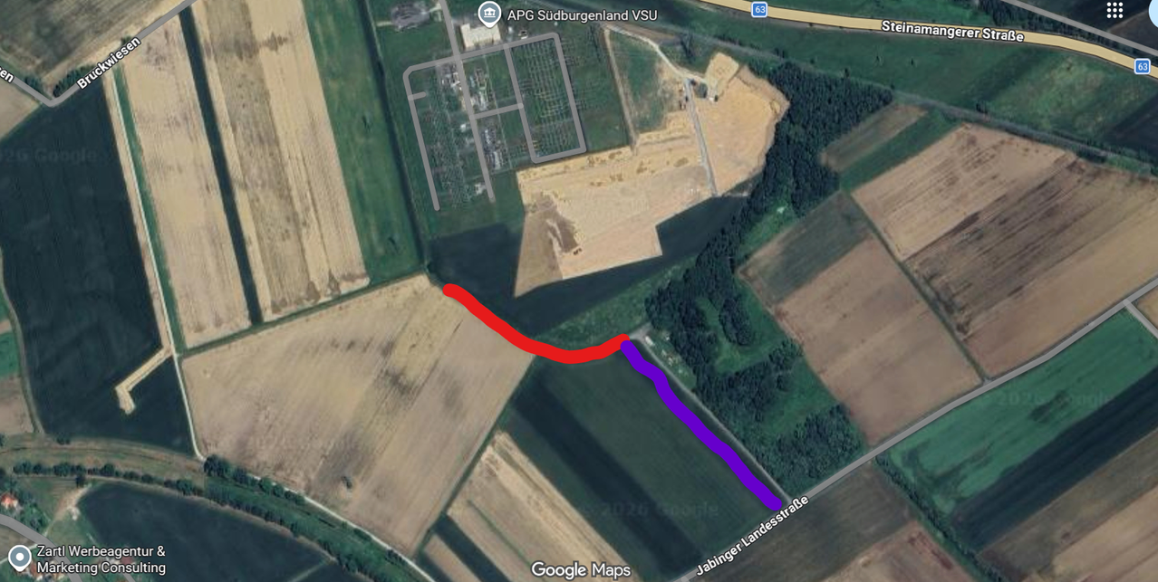 Luftaufnahme eines ländlichen Gebiets mit einer Straße namens Jabbinger Landesstrasse, einer roten Linie, die eine Route anzeigt, und einer Baustelle mit der Bezeichnung APG Südburgenland VSU.