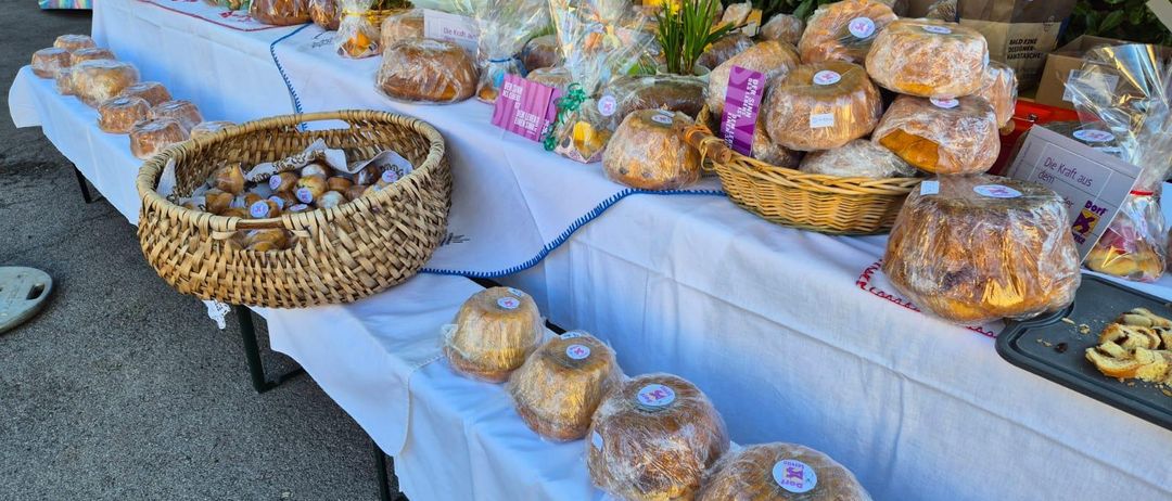 Ein Tisch mit mehreren Reihen von verpacktem Brot und Gebäck zur Schau gestellt, einige in Körben, mit Blumen und einer Tür im Hintergrund.