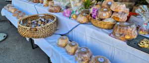 Ein Tisch mit mehreren Reihen von verpacktem Brot und Gebäck zur Schau gestellt, einige in Körben, mit Blumen und einer Tür im Hintergrund.