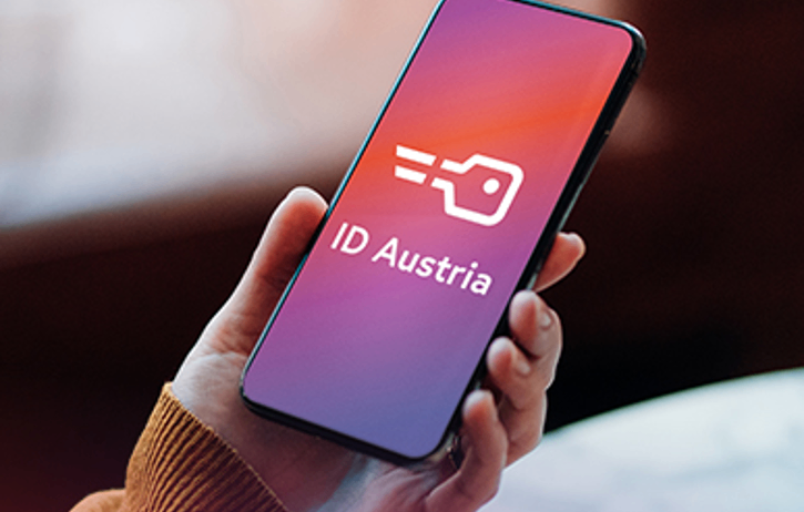 Eine Person hält ein Smartphone mit dem Symbol der ID Austria App, was auf digitale Identifikation hinweist.
