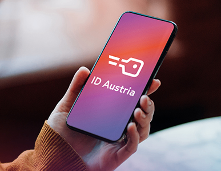 Eine Person hält ein Smartphone mit dem Symbol der ID Austria App, was auf digitale Identifikation hinweist.