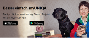Eine Frau in einem bunten Pullover sitzt auf einem Sofa, lächelt, mit zwei schwarzen Labradoren. Ein Hund trägt ein Halsband, und Bücher und ein rosa Objekt sind auf dem Tisch.