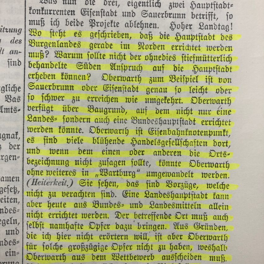 Das Bild zeigt ein historisches Dokument mit deutschem Text in Gelb und Schwarz. Es diskutiert die Errichtung einer Landeshauptstadt und erwähnt spezifische Orte wie Burgenland und Oberwarth. Es spricht sich gegen die Verlegung bestimmter Gilden aus und hebt wirtschaftliche Bedenken an. Der Text ist in kursiver Schrift gehalten, und einige Wörter sind gelb hervorgehoben.