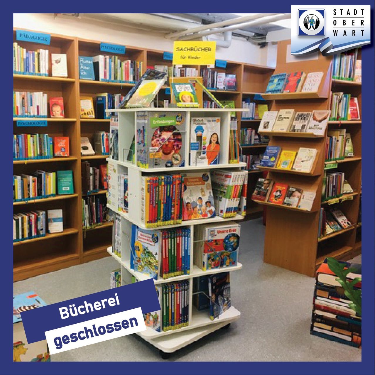 Bibliotheksregale gefüllt mit Kinderbüchern, eines zeigt prominent 'Sachbücher für Kinder'. Der Raum hat Holzregale, ein Logo oben rechts und ein Schild, das 'Bücherei geschlossen' anzeigt.