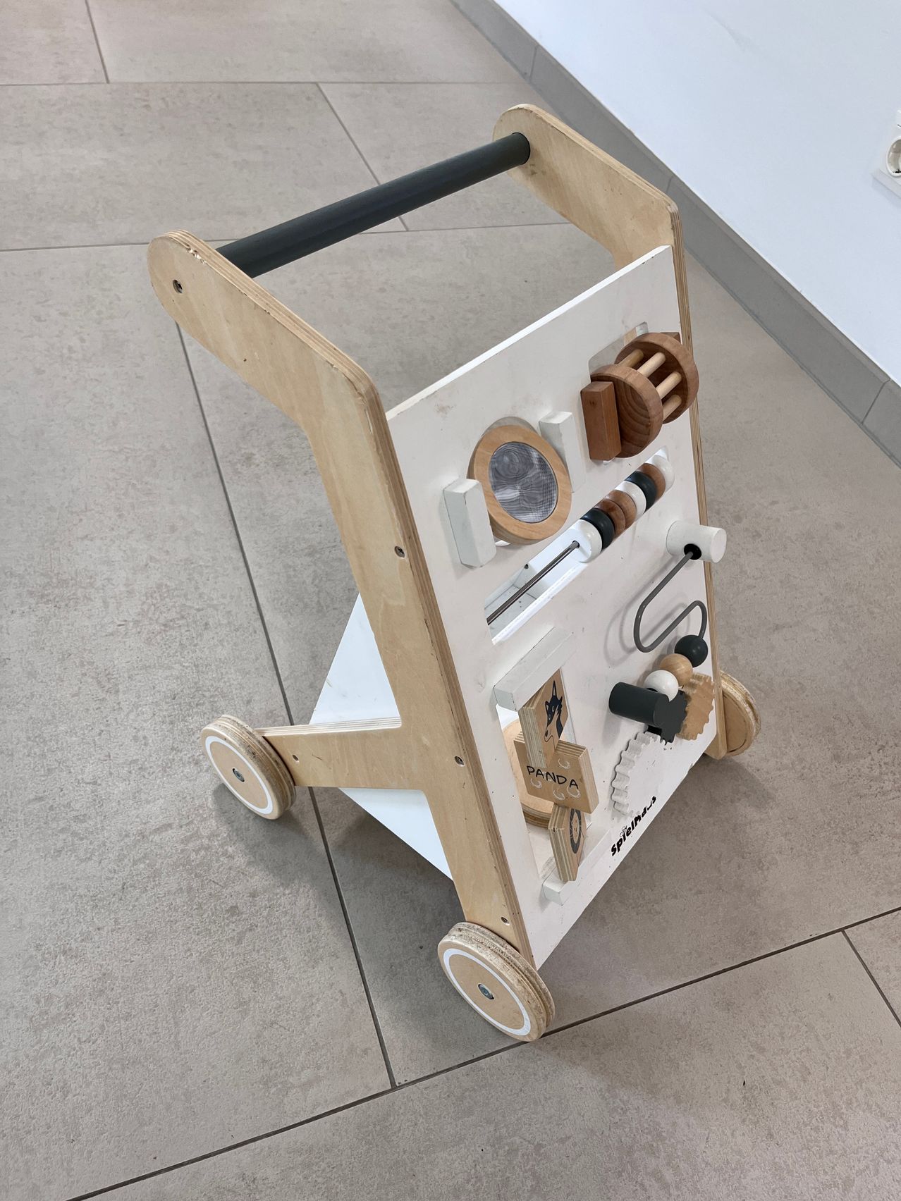 Ein hölzerner Spielzeugwagen mit verschiedenen Holzteilen, einschließlich eines hölzernen Rades, eines hölzernen Rings und eines hölzernen Balls. Der Wagen hat einen Griff und Räder.
