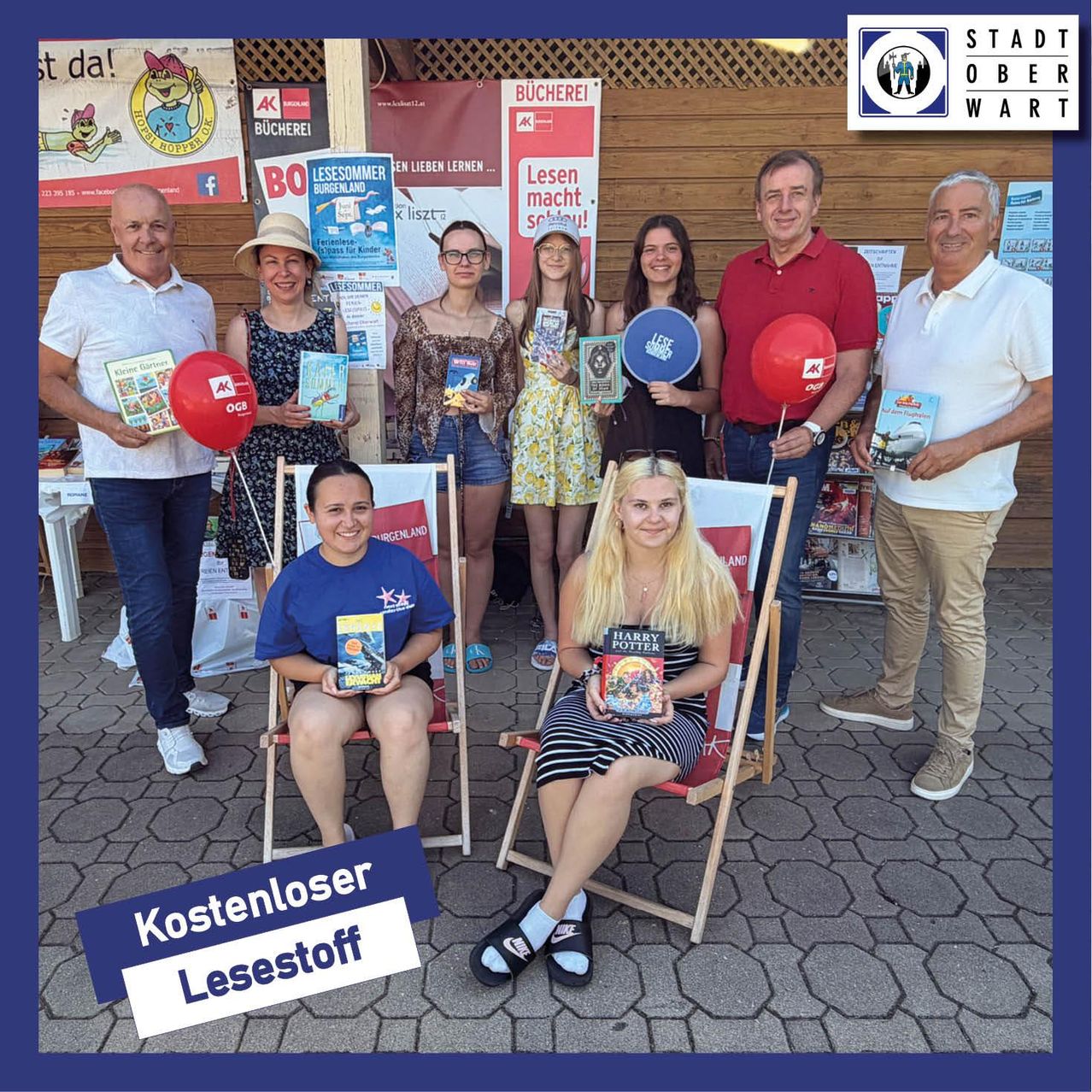 Mehrere Menschen stehen zusammen und halten Bücher. Einer hält einen Ballon. Ein Plakat sagt 'Lesen macht süchtig'. Ein anderes Plakat hat 'Bücherei'. Es gibt ein Wasserzeichen 'Kostenloser Lesestoff'.