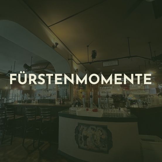 Eine Bartheke mit mehreren Flaschen, Gläsern und anderen Gegenständen darauf. Das Wort 'Fürstenmomente' ist prominent im Bild zu sehen.