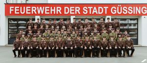Eine Gruppe von Stadtverteidigungsoffizieren in Uniform posiert für ein Foto vor einem Gebäude.