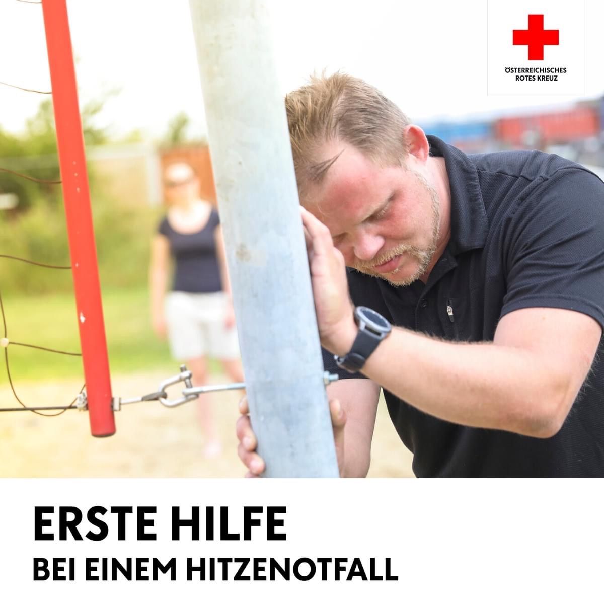 Ein Mann in einem schwarzen Shirt hält einen Pfosten mit seiner Hand, anscheinend in Not. Im Hintergrund erscheint ein verschwommenes Bild einer Frau. Unten steht der Text 'Erste Hilfe bei einem Hitzschlag'.