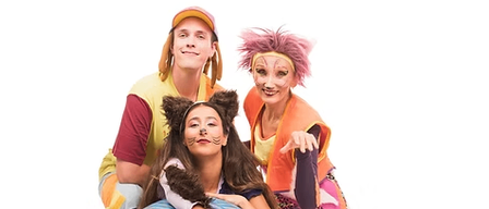 Drei Menschen posieren für ein Foto mit einem großen blauen Ball. Sie tragen alle Kostüme und Make-up. Die Person in der Mitte sitzt auf dem Ball und hat Katzenohren auf dem Kopf. Die Person auf der rechten Seite trägt eine rosa Perücke.