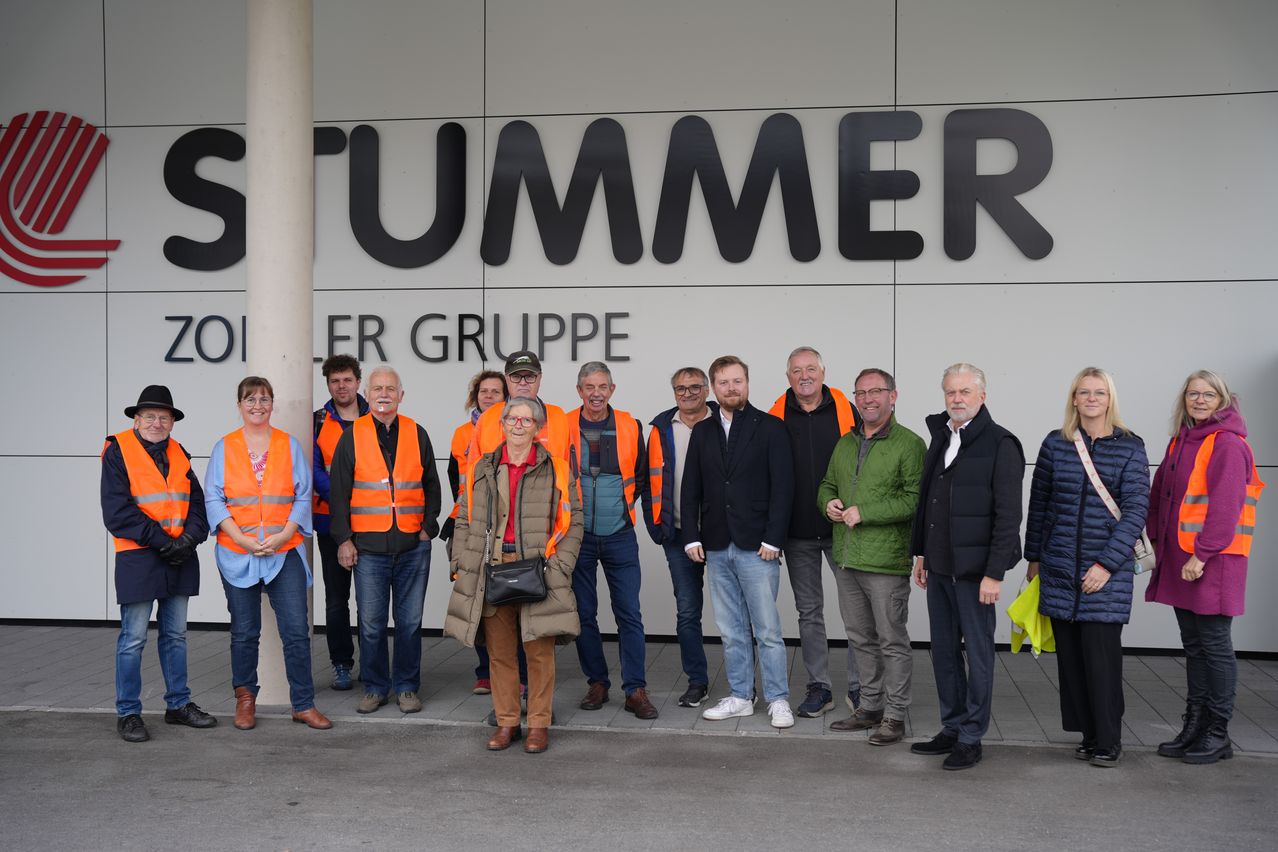 Eine Gruppe von Menschen, einige in orangenen Westen, steht vor einem Gebäude mit dem Wort 'Sommer' darauf.