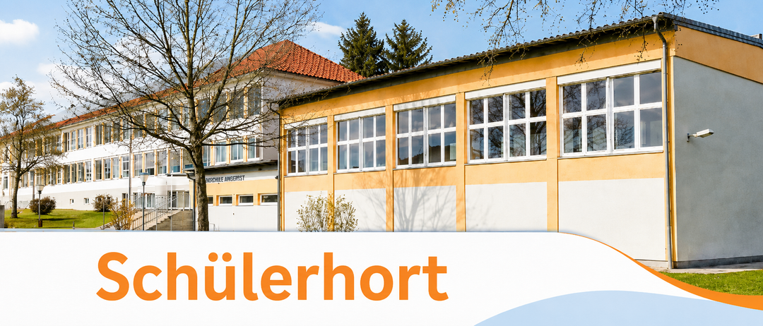 Ein Schulgebäude mit rotem Dach und Glasfenstern steht vor einem Baum. Das Gebäude ist gelb und weiß gestrichen.
