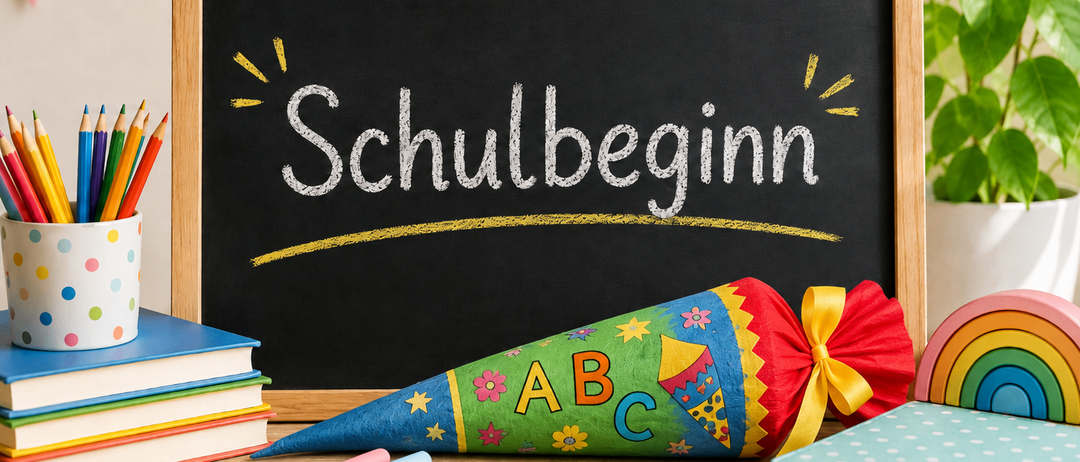 Ein Schultafel mit dem Wort 'Schulbeginn' in weißer Kreide geschrieben, begleitet von einem bunten Kegel, Büchern und Kreidestücken auf einem Holztisch.