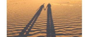 Ein Poster zeigt eine Wüstenszene mit Schatten von zwei Menschen. Es enthält den Text Bleib bitte nicht so, wie du bist! Die Überschrift lautet Volkmarkt - St. Magdalena und März / April 2026.