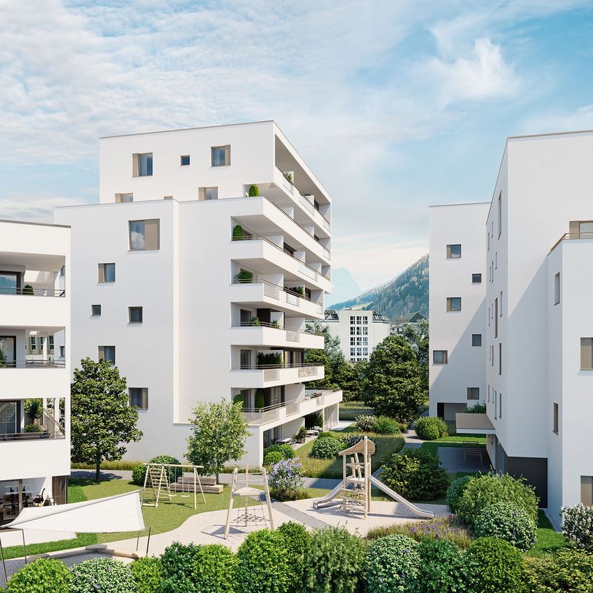 Ein Blick aus der Vogelperspektive auf einen modernen Apartmentkomplex mit mehreren Gebäuden, Balkonen, Grünflächen und einem Kinderspielplatz unter einem blauen Himmel.