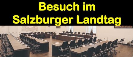 Ein großer Konferenzraum mit Reihen von Tischen und Stühlen. Der Textüberlagerung steht 'Besuch im Salzburger Landtag'. Der Raum scheint leer zu sein.