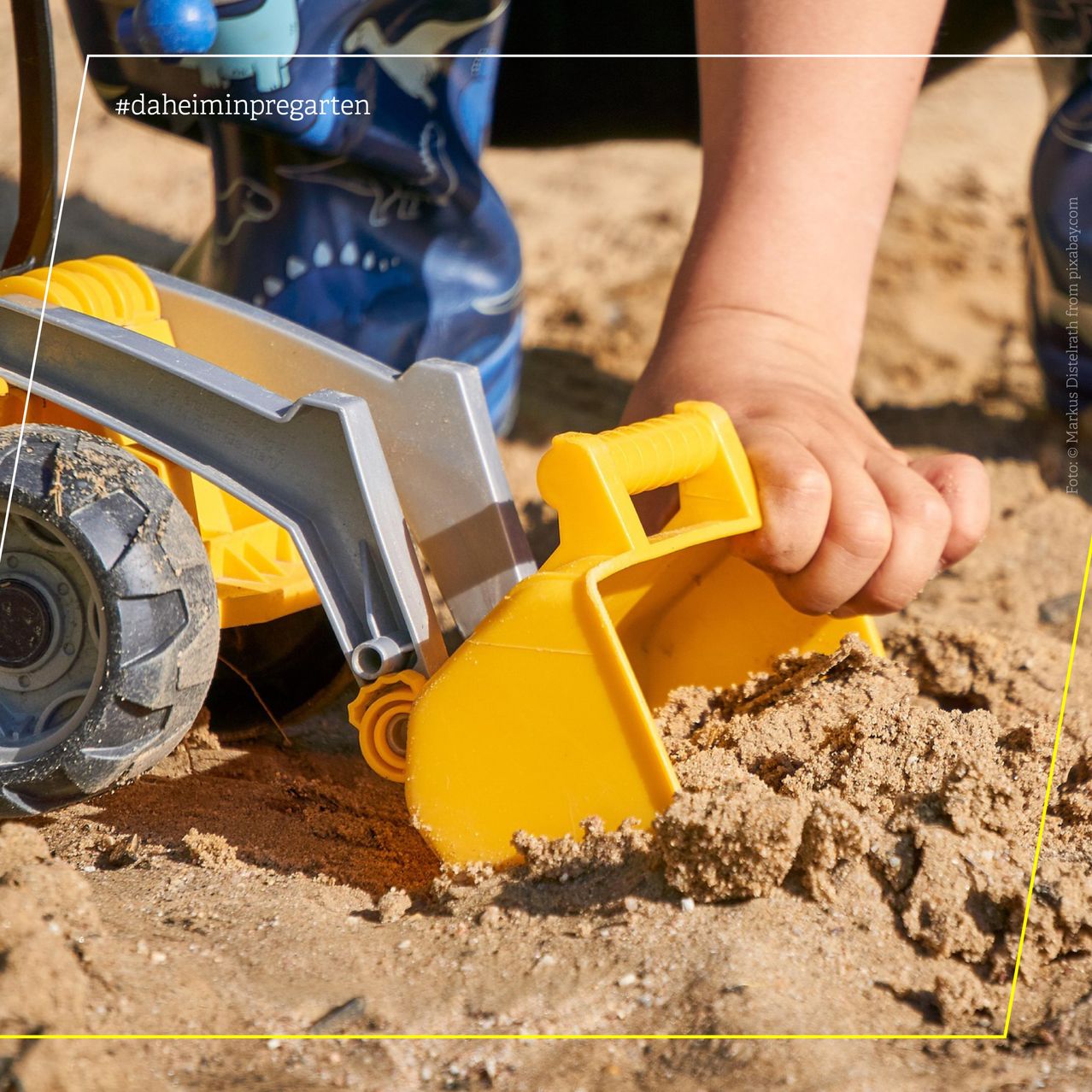 Kinderhände spielen mit einem Spielzeugbagger in der Sandkiste
