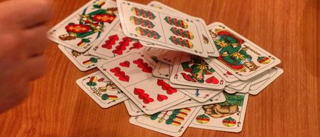 Ein Stapel Spielkarten auf einem Holztisch, mit verschiedenen Farben, Zahlen und Symbolen, in gemischten Positionen angeordnet.