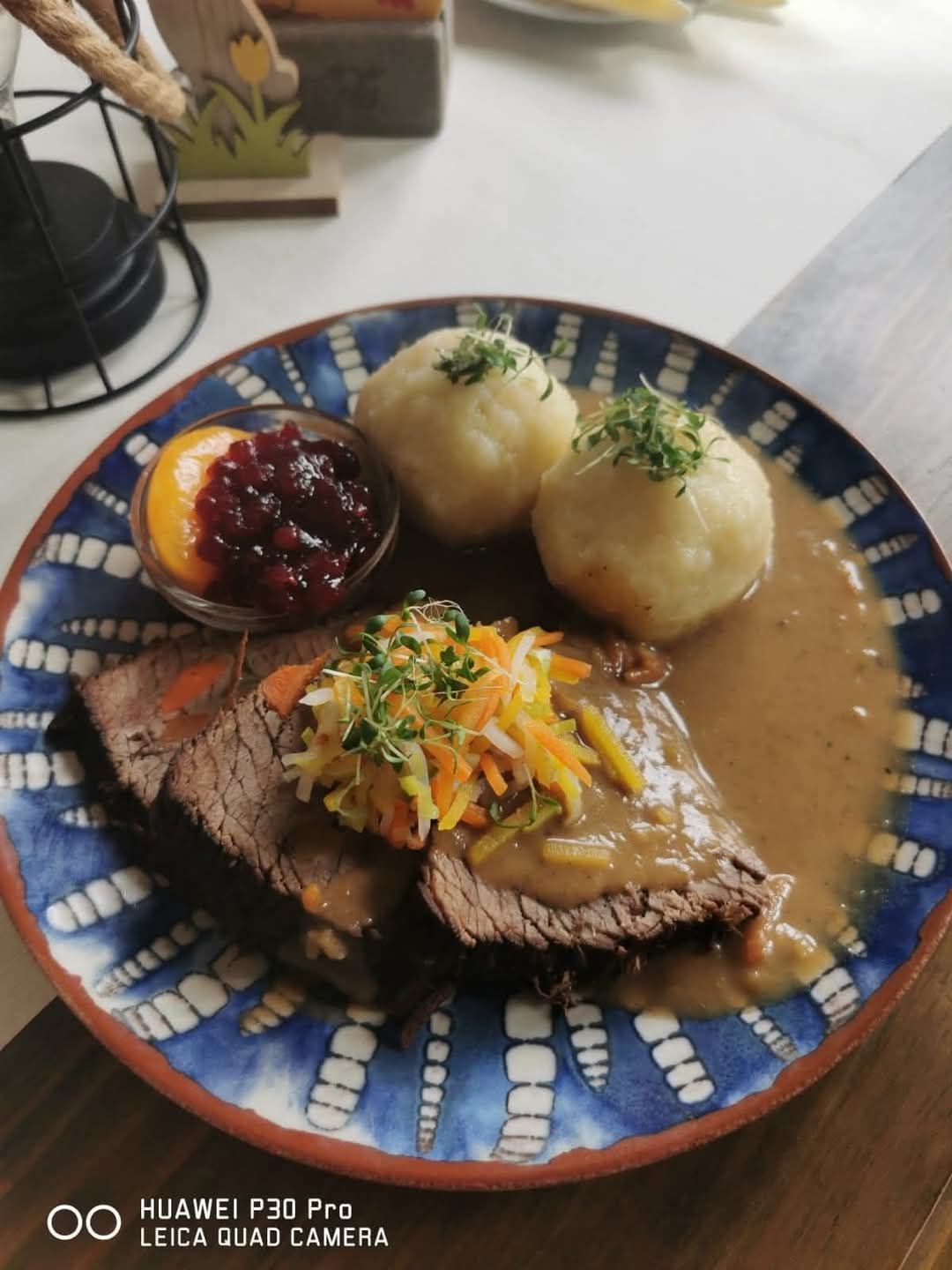 Ein Teller mit Roastbeef, Kartoffelpüree, Cranberry-Sauce und einem bunten Salat, serviert auf einem blauen Teller mit aufwendigen Mustern.