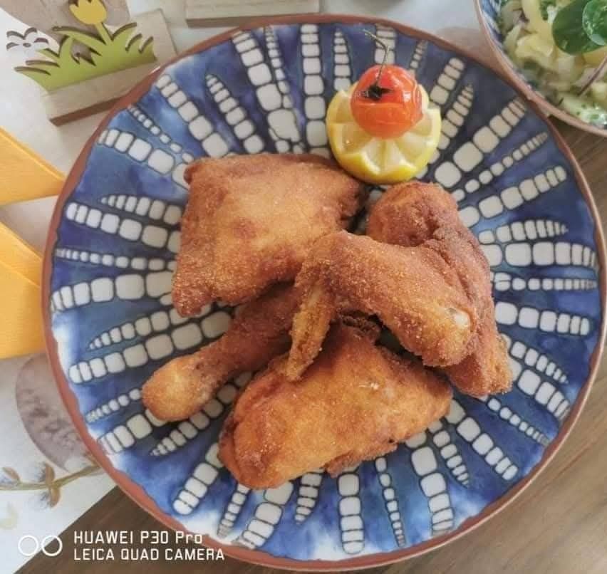 A plate of fried chicken pieces with a lemon slice on top, on a blue and white patterned plate.