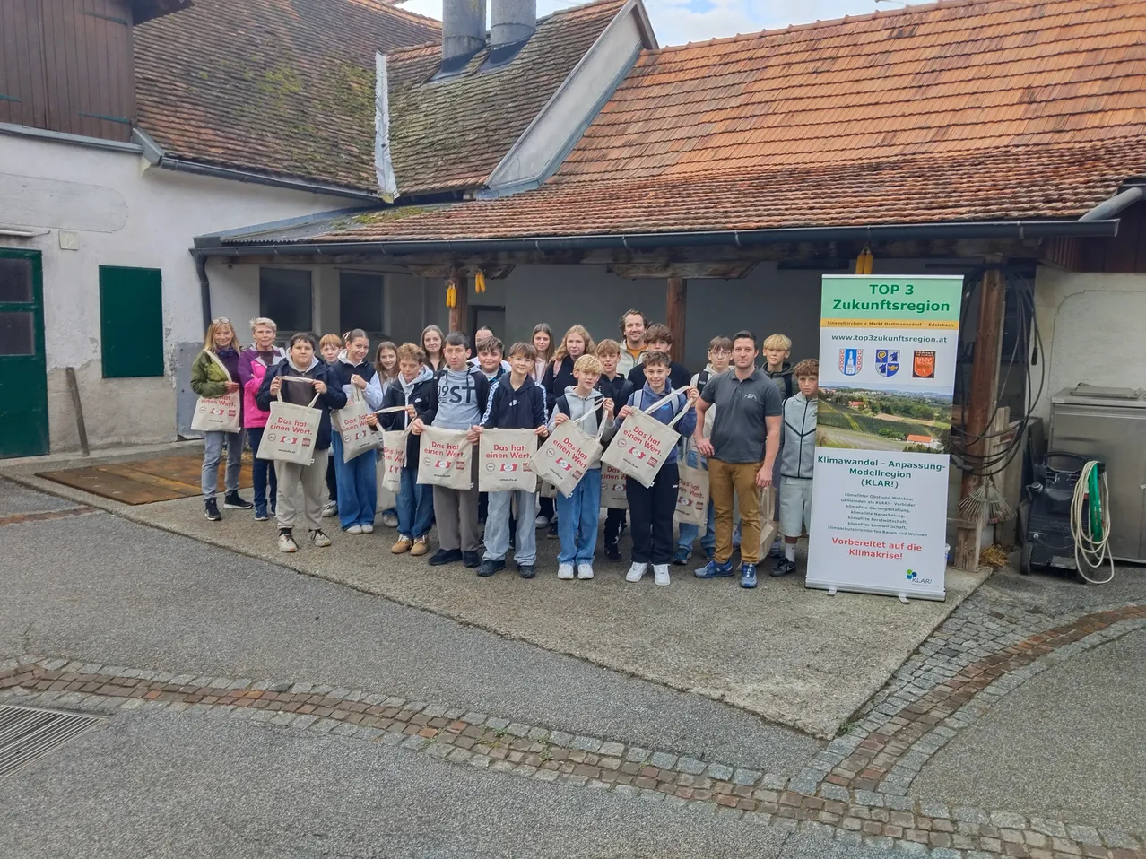 Eine Gruppe von Menschen steht vor einem Gebäude, hält Taschen und lächelt für ein Foto.