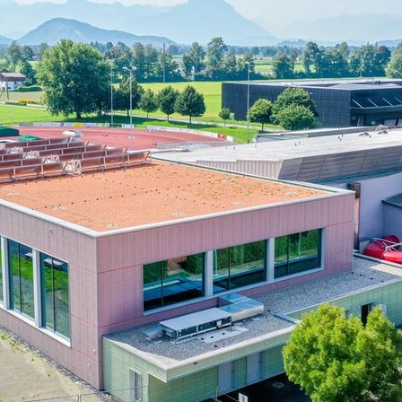 Ein Luftbild eines modernen Gebäudes mit Solarmodulen auf dem Dach. Es verfügt über eine rote Wasserrutsche, eine Rutsche und einen Swimmingpool.
