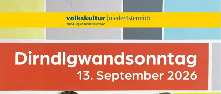 Zwei Frauen stehen nebeneinander vor einer bunten Wand mit dem Text 'Dirndlgwandsonntag 13. September 2026'. Beide tragen Blumenkleider und eine hat eine Brille.