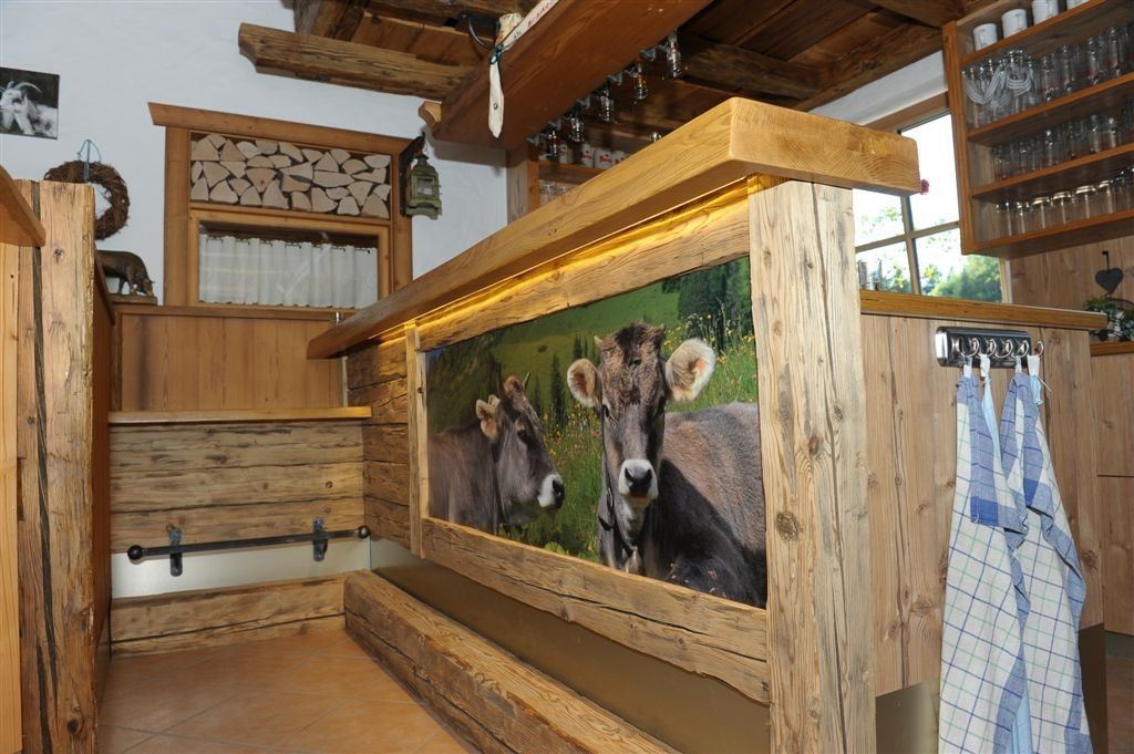 Eine rustikale Holzbar mit einem Bild von zwei Kühen. Die Bar steht an einer Holzwand mit einem Fenster und einer offenen Tür.
