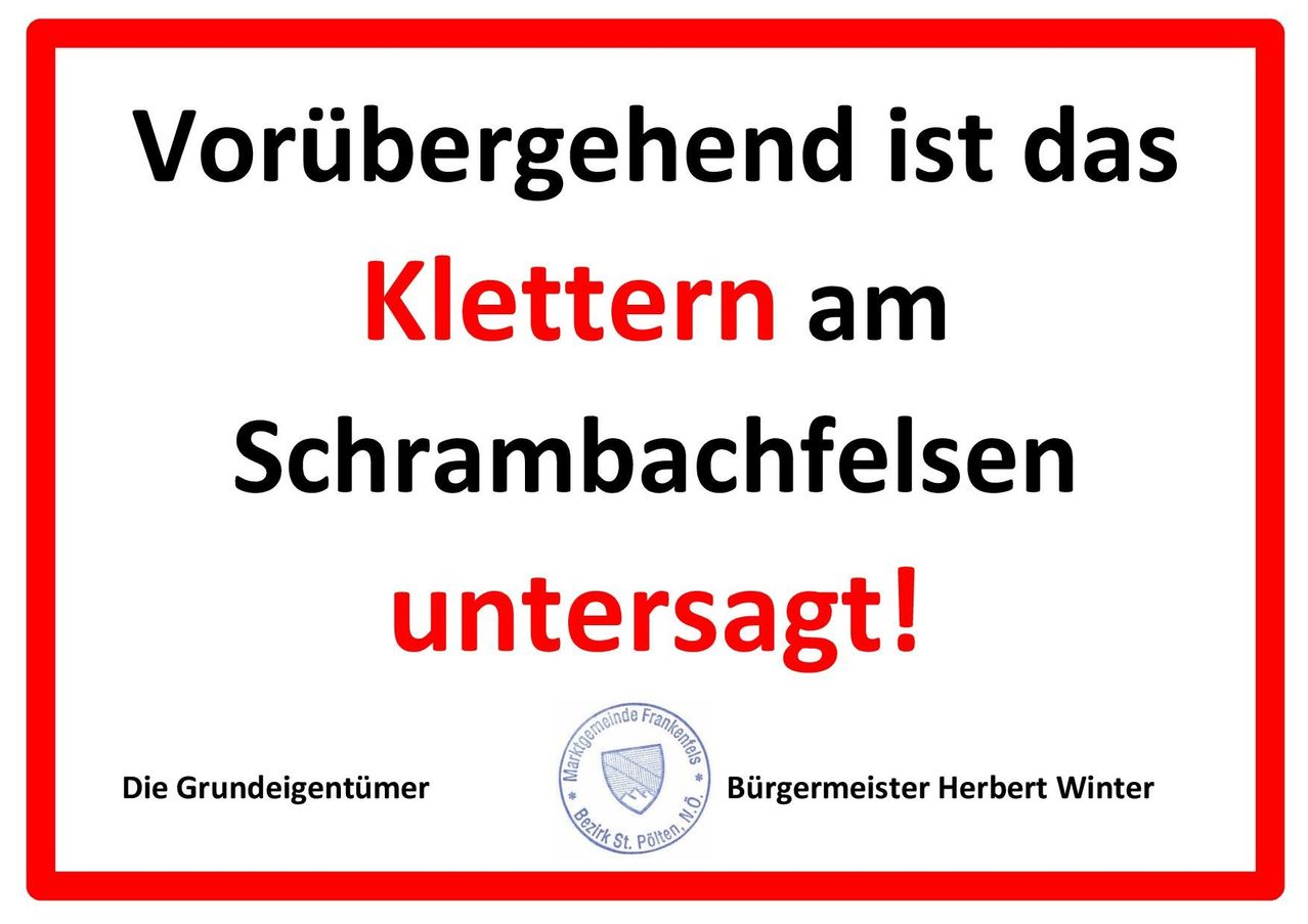 Ein Schild in deutscher Sprache teilt mit, dass das Klettern am Schrambachfelsen vorübergehend untersagt ist. Der Text wird von einem Logo und dem Namen des Bürgermeisters, Herbert Wint, begleitet.