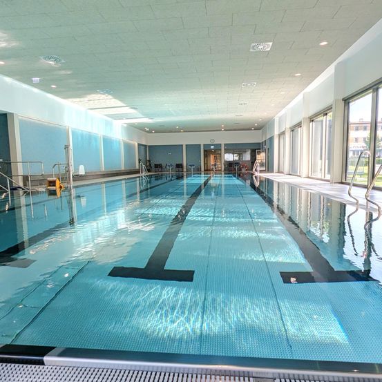 Ein leerer Innenpool mit blauen Wänden und einer Decke. Der Pool ist sauber und gepflegt, mit einer schwarzen Bahnlinie.