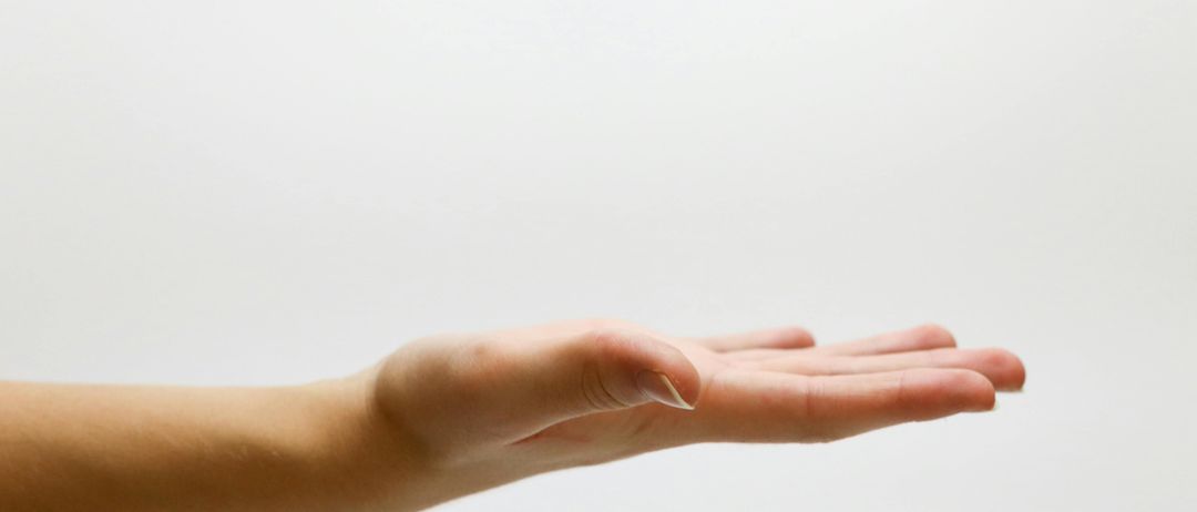 Ein Nahaufnahme einer menschlichen Hand mit leicht gebogenen Fingern, die auf einem weißen Hintergrund ruht. Die Haut erscheint glatt mit sichtbaren Venen.