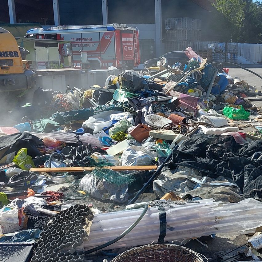 Ein Haufen verschiedener Abfallmaterialien, einschließlich Plastiktüten, Netze und anderer Trümmer, mit einem Feuerwehrfahrzeug im Hintergrund.