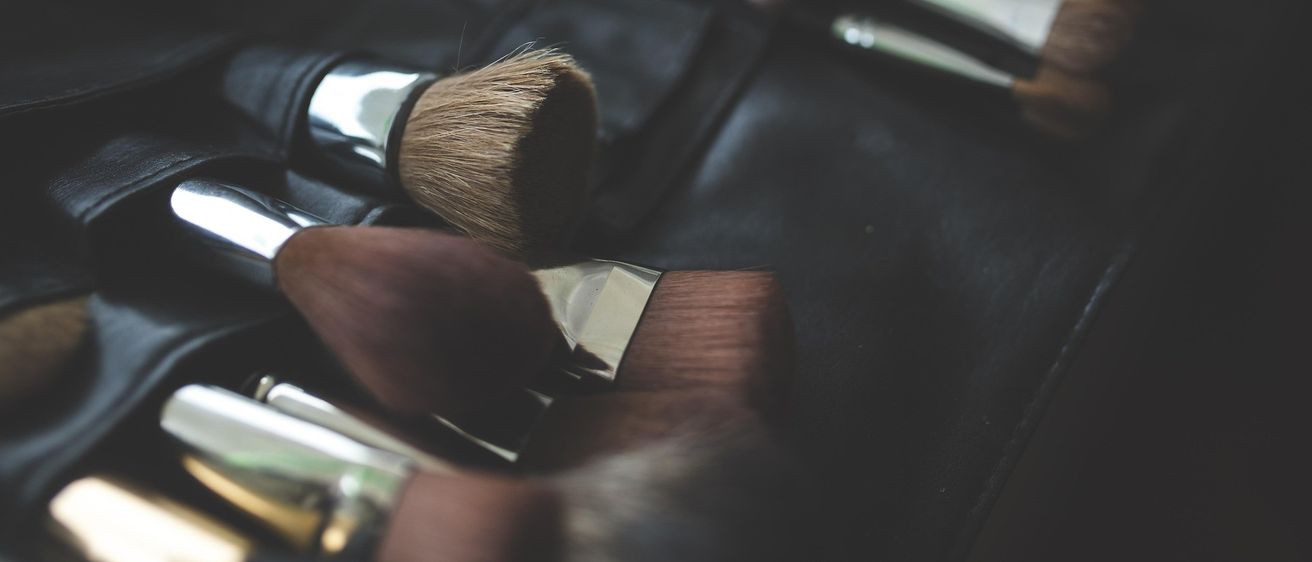 Eine Sammlung von Make-up-Pinseln in verschiedenen Größen und Formen, ordentlich in einem schwarzen Etui angeordnet. Die Pinsel haben Metallgriffe und weiche Borsten.
