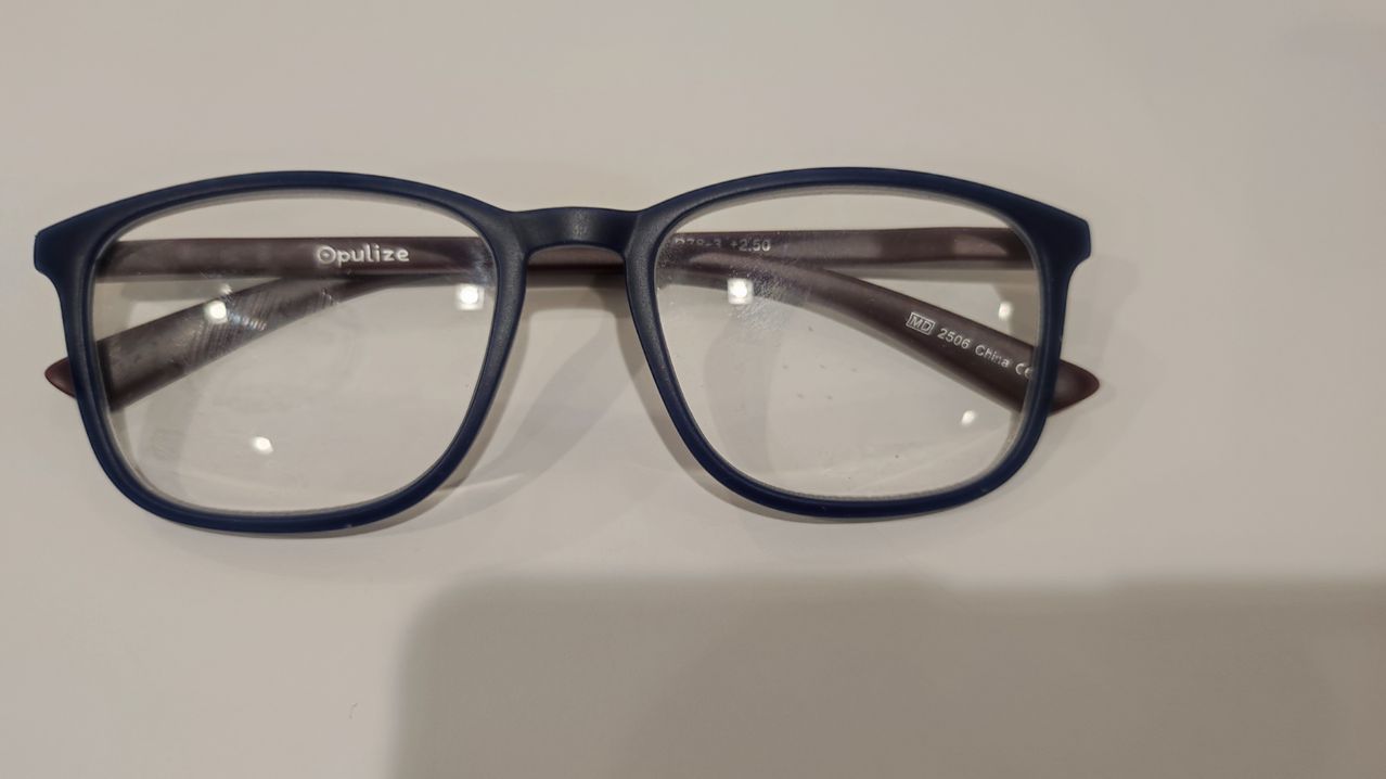 A pair of blue-framed eyeglasses with clear lenses, labeled with MD 2508, is displayed on a white background.