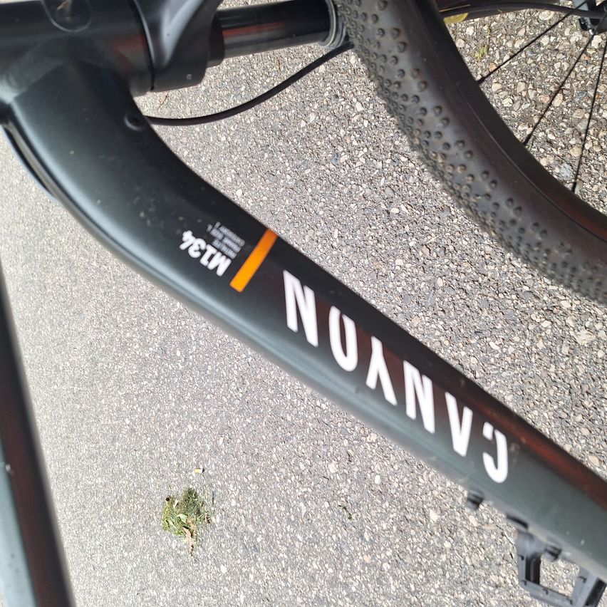 Close-up of a black bicycle with 'METU' and 'NUANCE' text on its frame. The wheel and some parts are visible.