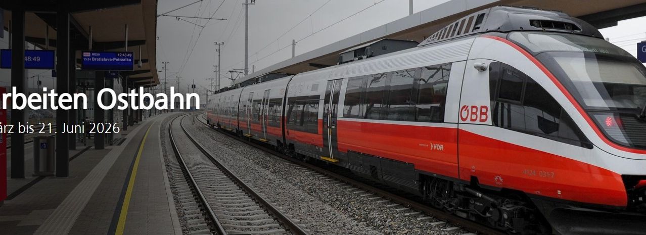 Ein roter und weißer Zug steht auf einem Bahngleis am Bahnhof, mit dem Wort OBB an seiner Seite.