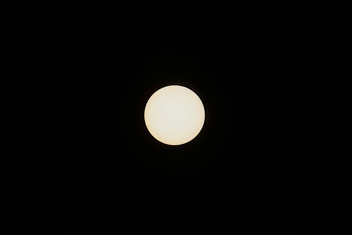 A bright, full moon illuminates the night sky, casting a soft glow on the surrounding darkness.