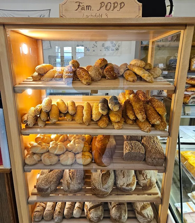 Eine Vitrine mit verschiedenen Brotsorten, darunter Baguettes, Brötchen und Laibe, unter warmer Beleuchtung.