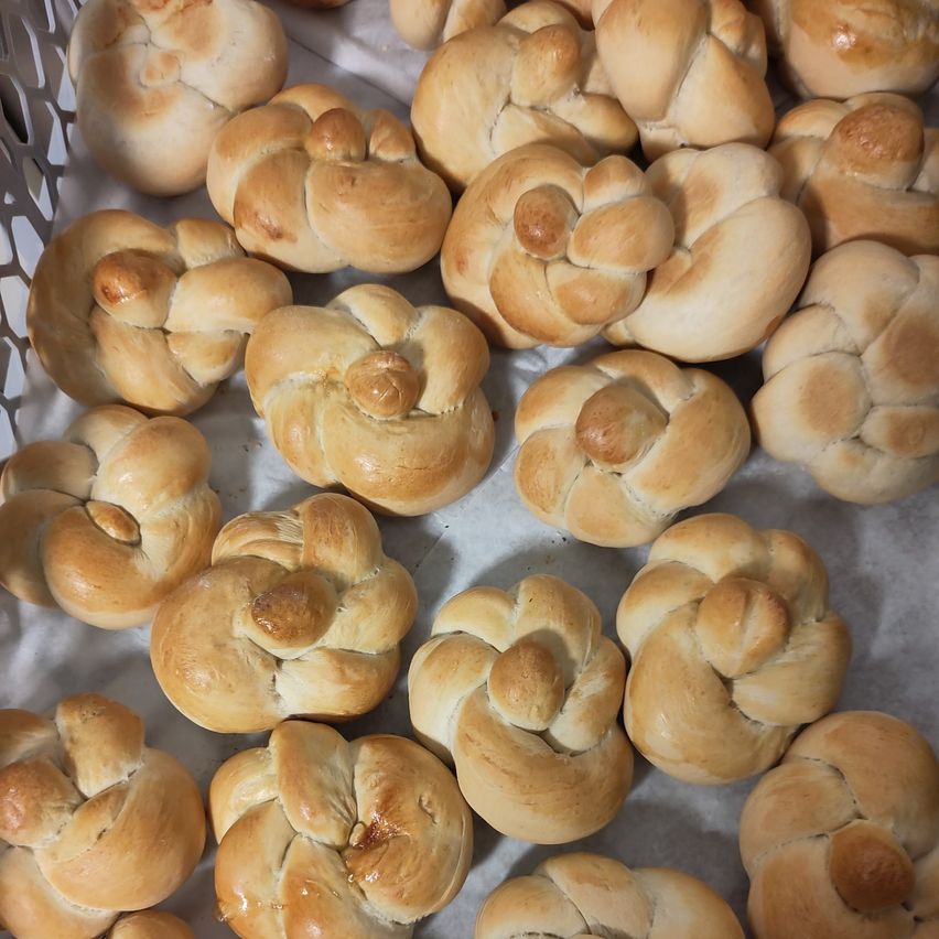 Eine weiße Oberfläche ist mit goldbraunen geflochtenen Laib Brot gefüllt, jeder kunstvoll verknotet und leicht glänzend.