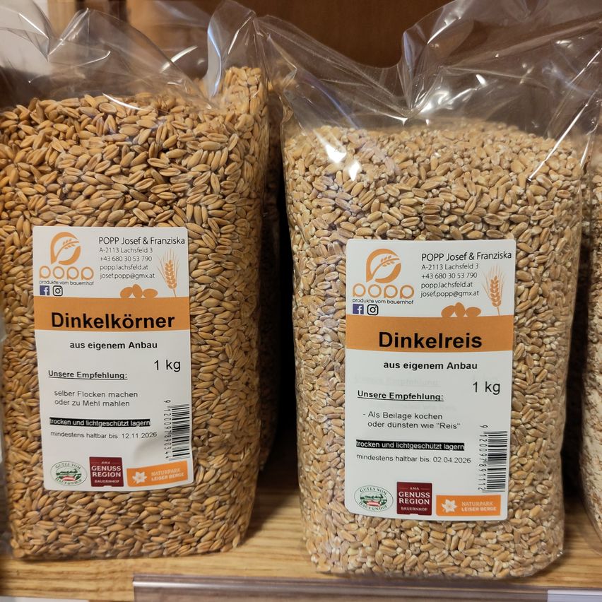 Zwei Tüten Dinkelkorn und Dinkelreis. Jede Tüte wiegt 1 kg. Dinkelkorn ist trocken und lichtgeschützt gelagert, haltbar bis 12.11.2026. Dinkelreis ist trocken und lichtgeschützt gelagert, haltbar bis 02.04.2026. Beide Tüten stammen von Popp Josef & Franziska.