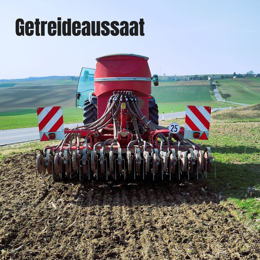 Ein roter Traktor mit der Nummer 25 auf der Front pflugt ein Feld. Der Traktor ist mit mehreren Rädern und einem großen Pflug ausgestattet. Das Feld ist von grünem Gras umgeben.