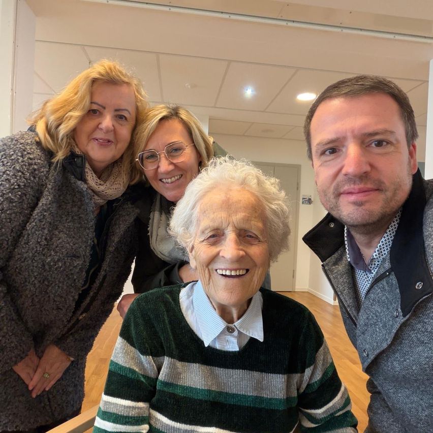 Drei Frauen und ein Mann posieren lächelnd für ein Foto. Die Frau in der Mitte trägt ein grün-weiß gestreiftes Sweatshirt. Der Mann steht rechts, während die Frau links einen Ring trägt.