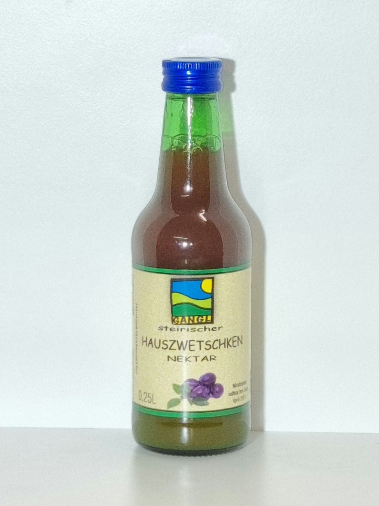 A bottle of Styrian home-made elderberry nectar, dark brown in color, with a blue cap. The label features a small illustration of a blue sun with rays and some purple elderberries.