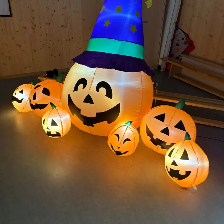 A large inflatable pumpkin with a witch hat and smaller pumpkins around it.