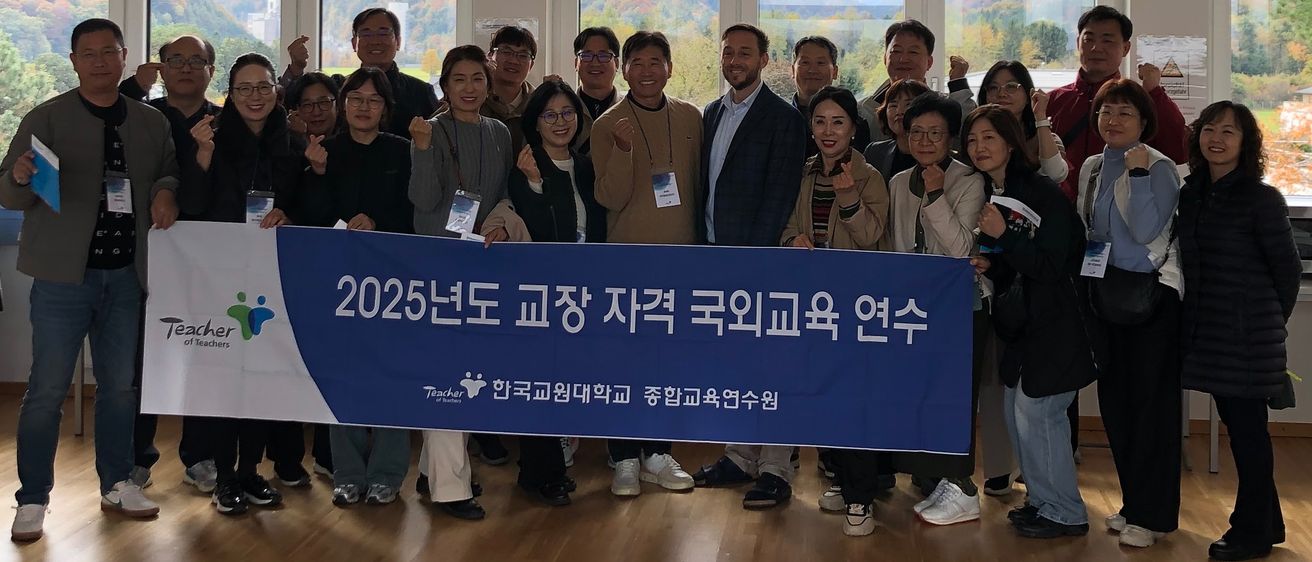 Eine Gruppe von Menschen posiert für ein Foto vor einem Fenster mit Blick auf Berge, während sie ein blaues Banner halten.