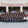 Ein Gruppenfoto der Feuerwehrleute aus Payerbach vor ihrem Feuerwehrhaus mit Feuerwehrautos im Hintergrund.