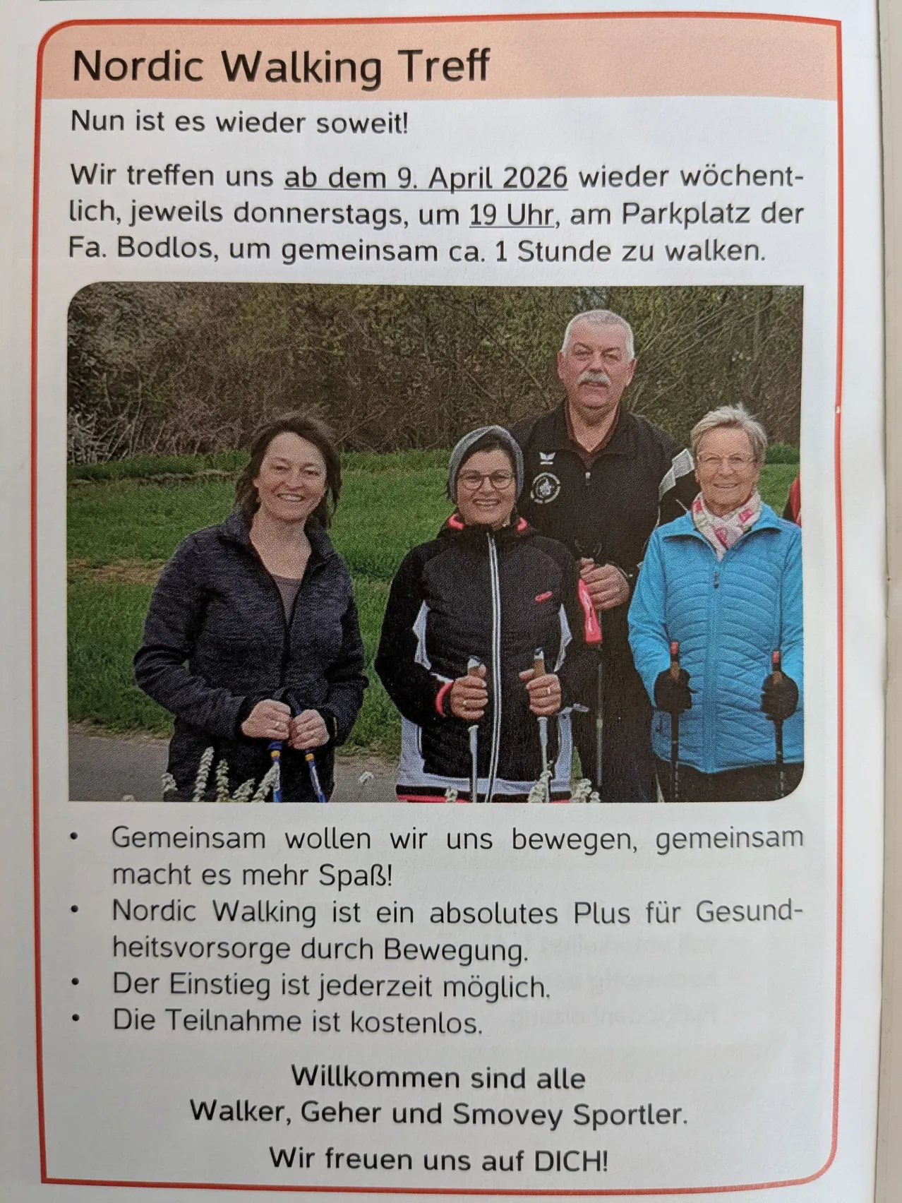 Vier Personen stehen zusammen und lächeln, während sie Nordic-Walking-Stöcke halten. Sie sind für einen Spaziergang gekleidet, der Mann trägt ein schwarzes T-Shirt und die Frauen Jacken. Sie sind draußen, auf einer Grasfläche mit Bäumen im Hintergrund.