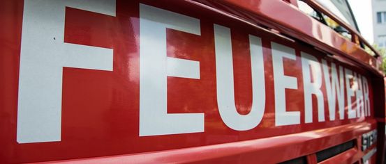 Nahaufnahme eines roten Feuerwehrwagens mit dem Wort 'FEUER' in weißen Buchstaben auf der Seite.