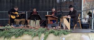 Eine Gruppe von Musikern tritt während des Advents in Wiener Neustadt auf der Bühne auf. Sie spielen verschiedene Instrumente.